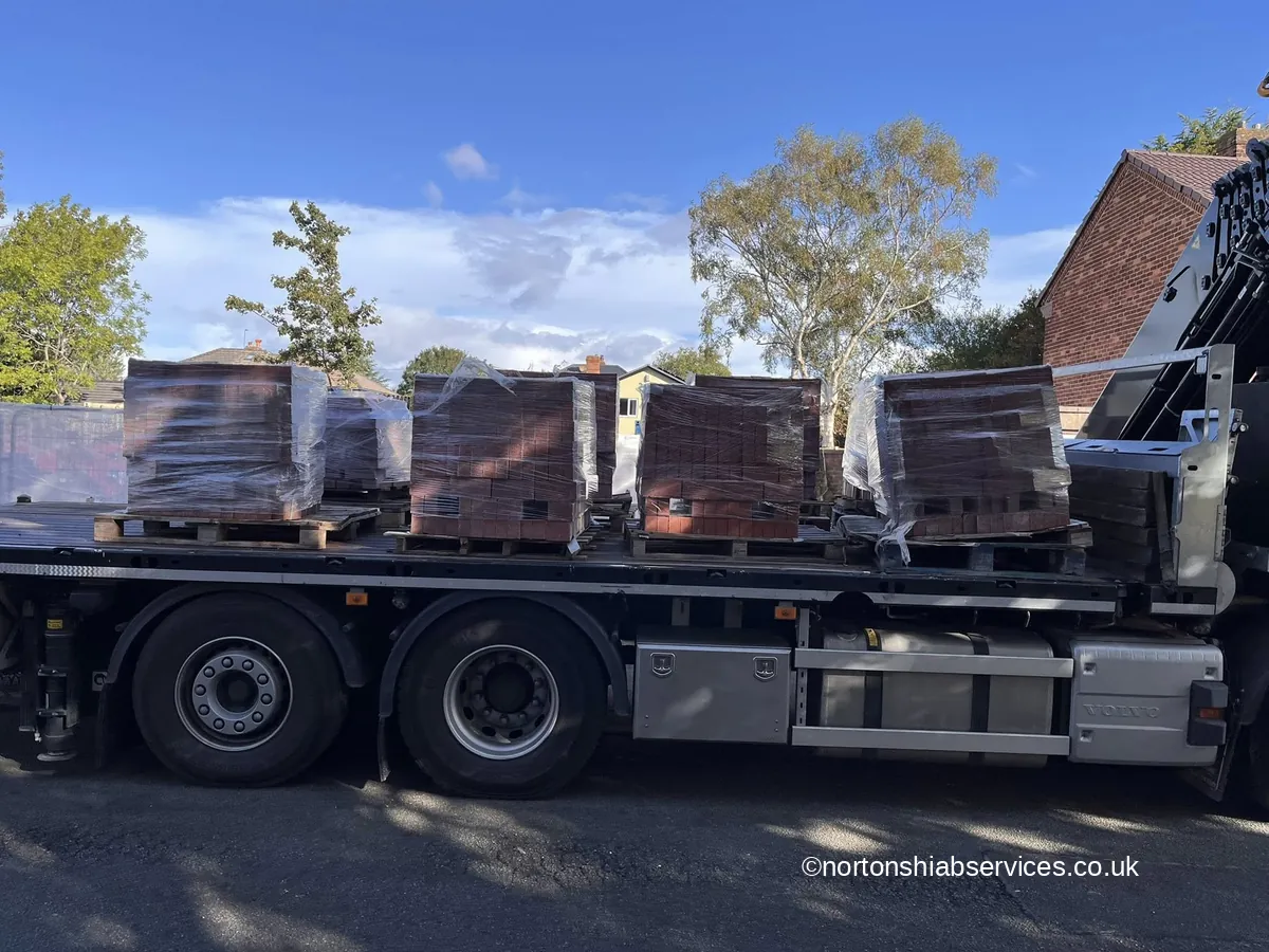 A Nortons flatbed trailer loaded with strapped and wrapped packs of bricks