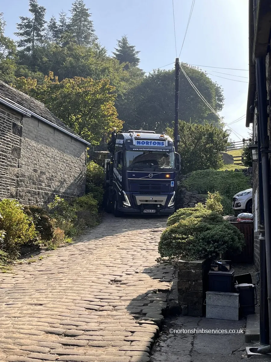 A Nortons lorry easing along a narrow cobbled lane between stone walls