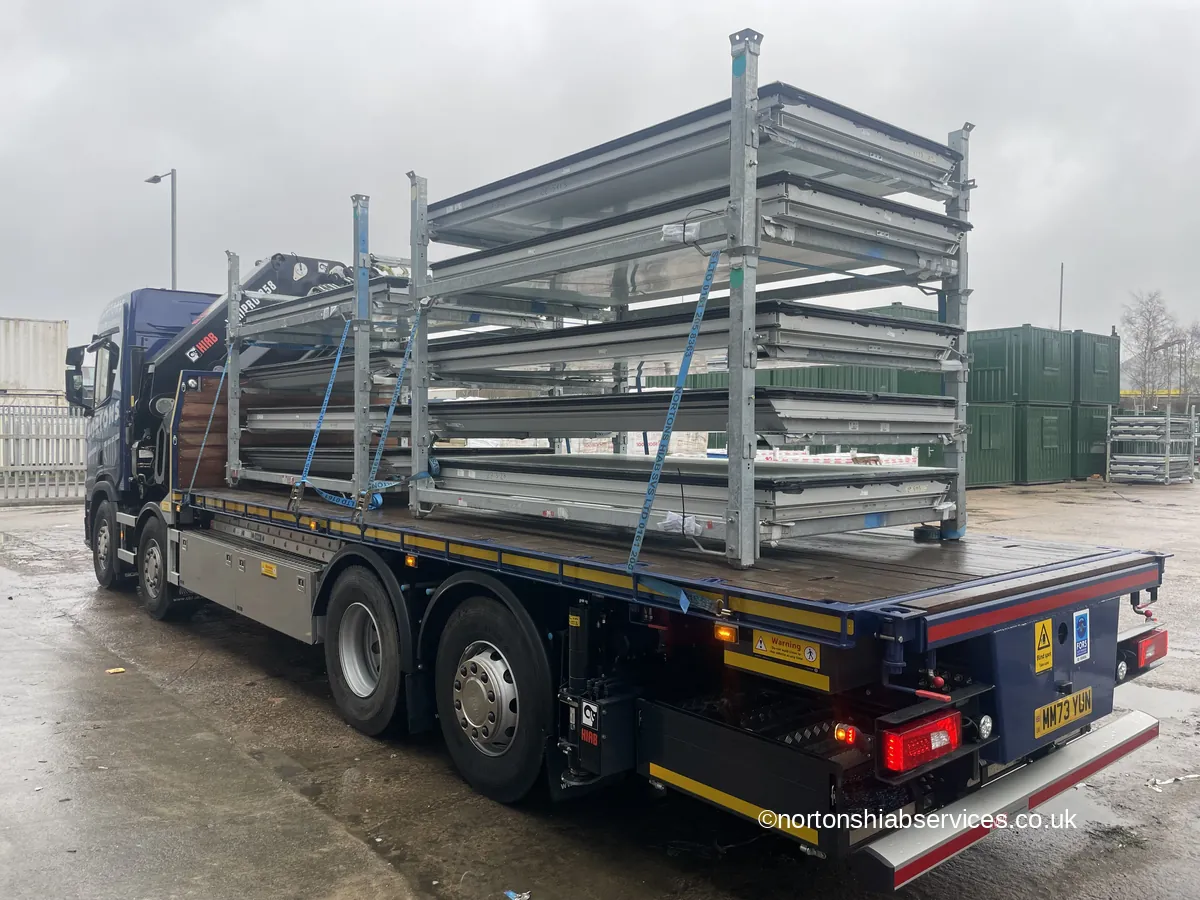 Galvanised stillage racks strapped along the deck of a Nortons flatbed