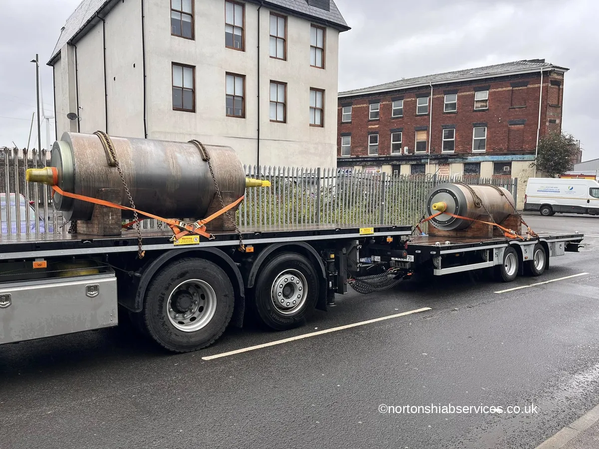 A large steel tank strapped to a Nortons drawbar trailer on a street
