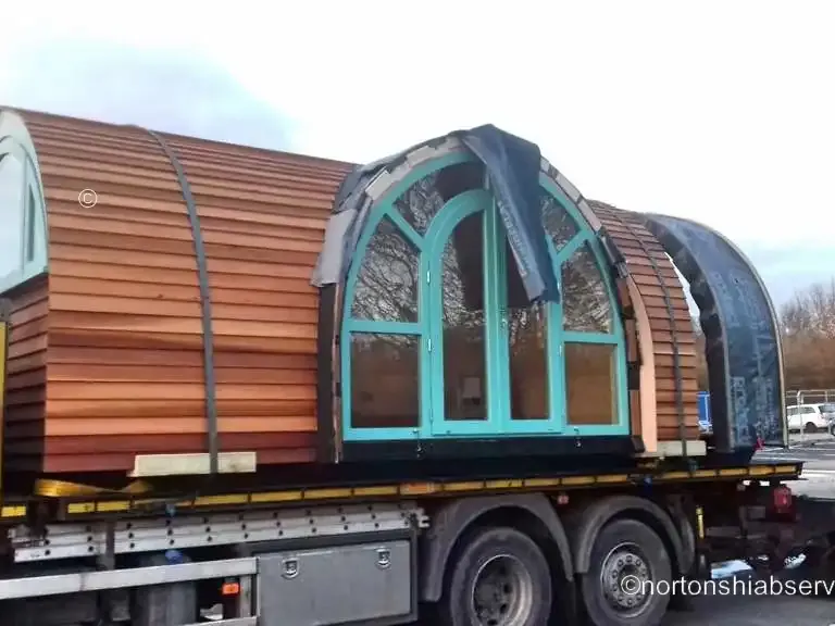 A timber pod with arched windows strapped down on a Nortons flatbed