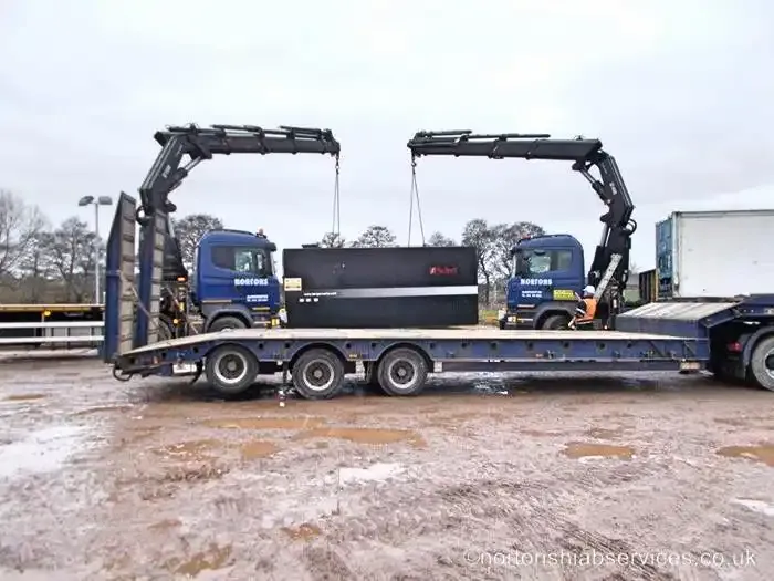 Two Nortons lorries standing on a yard with a dark unit on the deck between them