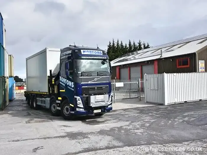 A Nortons Volvo with a white unit on the bed, standing in a fenced compound