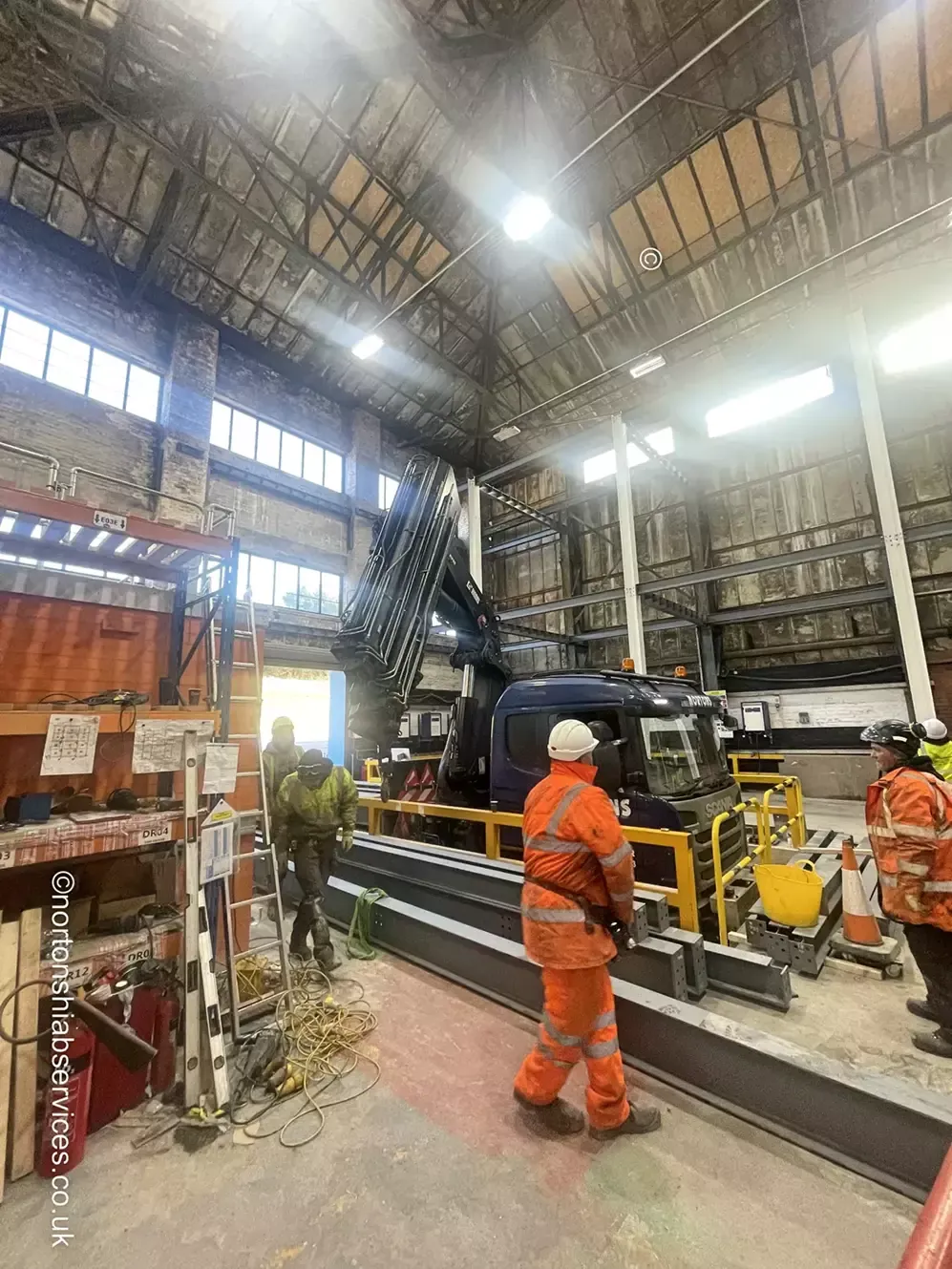 Nortons crane lifting a steel beam inside a building