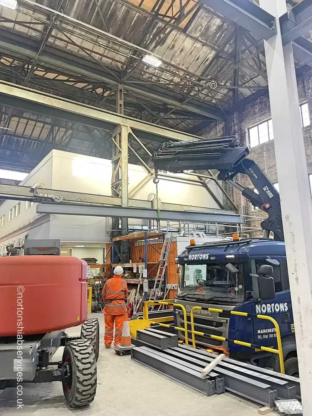 Steel beam being lifted into a building frame by a Nortons hiab