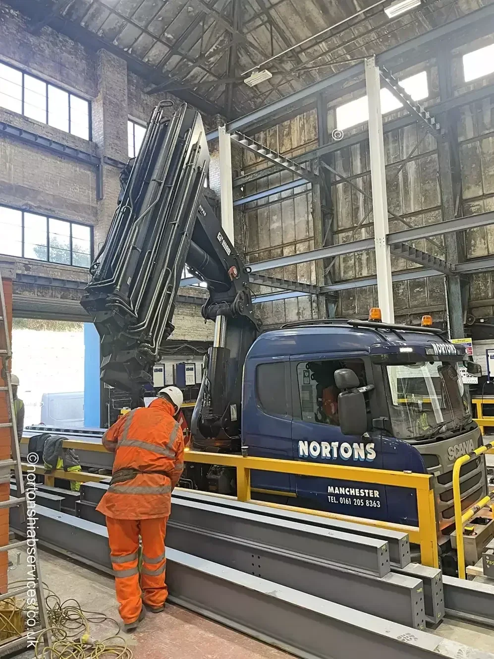 Nortons crane lifting a steel beam over the lorry cab