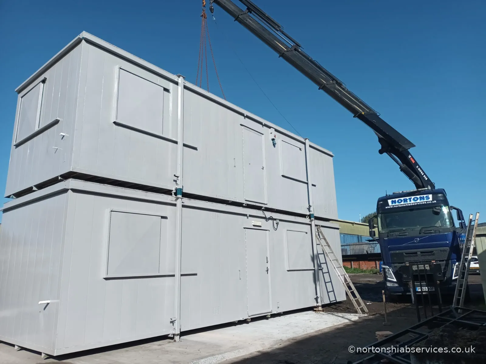 Portable cabins double stacked and linked on a prepared base, with the Nortons crane still slung above them