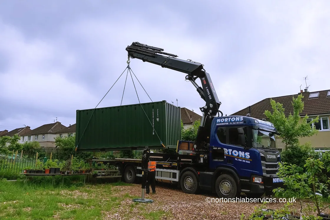 Nortons hiab lowering a steel unit over a fence onto its base