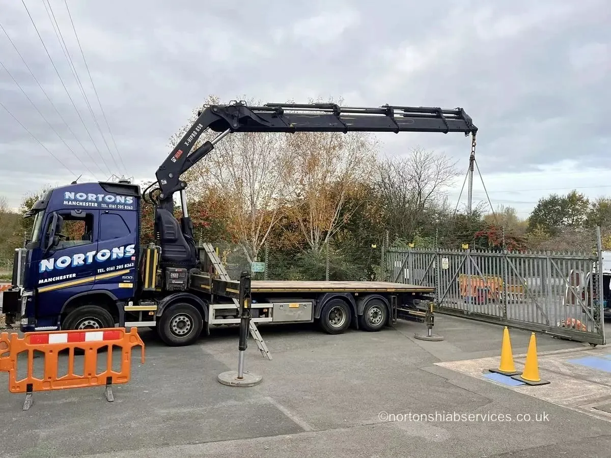 Nortons hiab crane reaching over a site fence to place a load