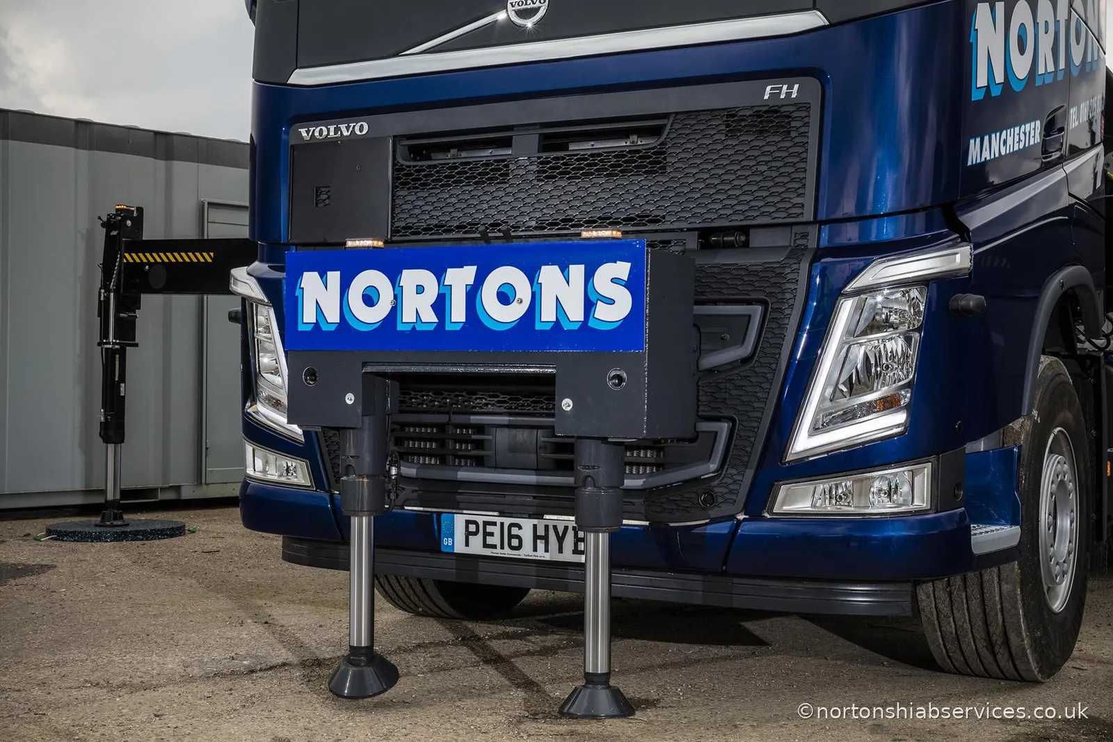 The front of a Nortons Volvo unit with its stabiliser legs down on the yard and the crane behind