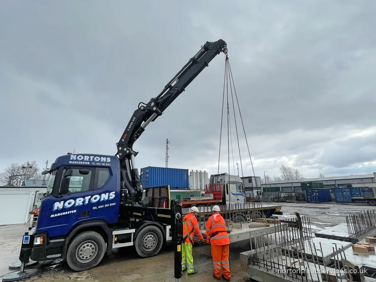 Nortons eight wheel rear steer rigid on its legs, loader crane behind the cab, setting a precast unit down