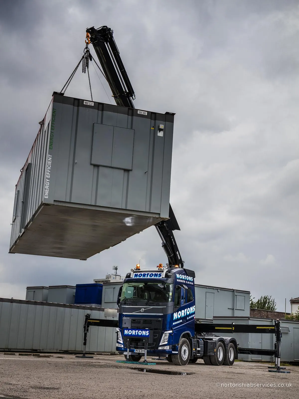 Nortons Volvo hiab lifting a site cabin clear of the ground at the Manchester yard