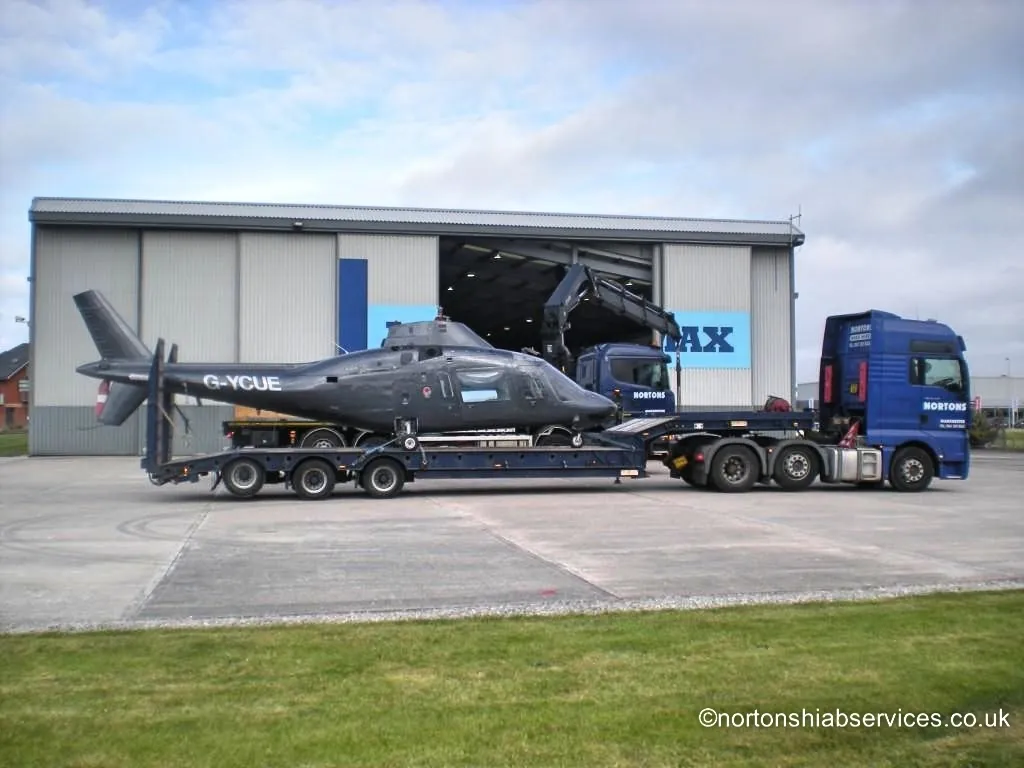 Nortons low loader carrying a helicopter away from a hangar at Blackpool Airport