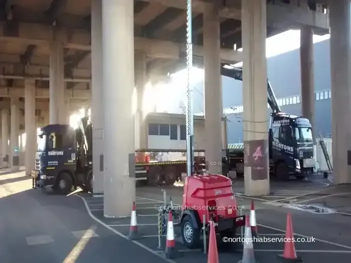Two Nortons hiab lorries working beneath a motorway viaduct