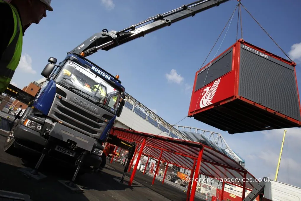 A red Liverpool Football Club coffee bar container lifted off the trailer on a Nortons Scania hiab at Anfield