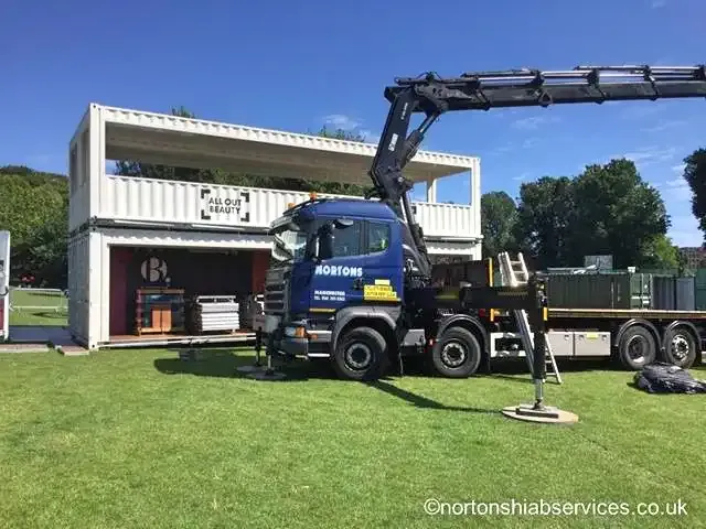 Container unit opened out on grass at a festival site with a Nortons hiab alongside