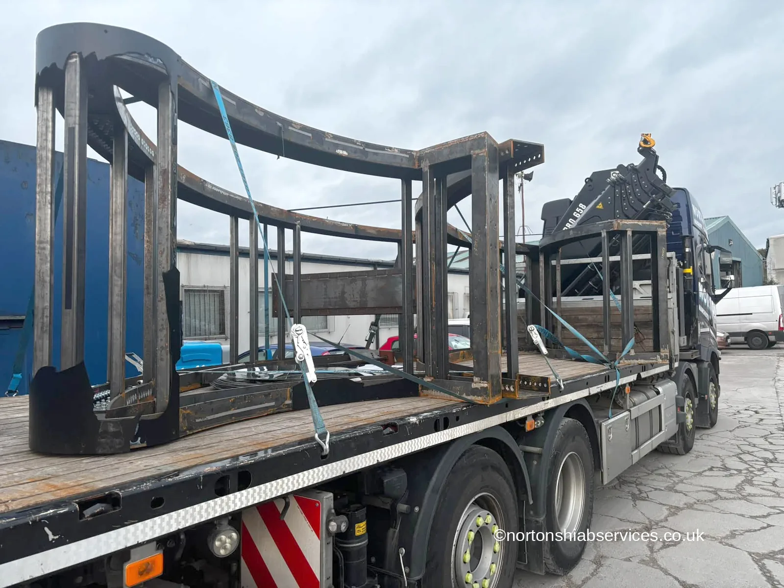 The curved steel stand of a giant tambourine installation strapped on the deck of a Nortons hiab lorry