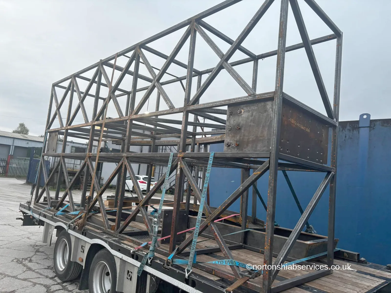 The braced steel frame of a giant tambourine installation strapped on a Nortons drag trailer