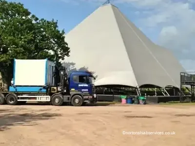 A Nortons wagon and drag loaded with cabins standing beside the large tent at the festival site