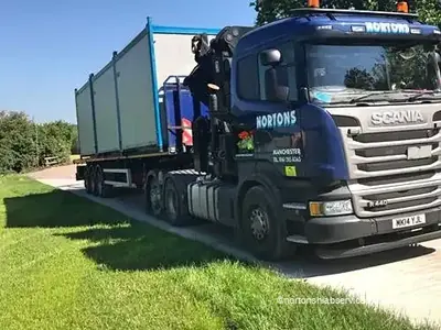A Nortons Scania hiab with site cabins on the deck standing on grass at the festival site