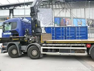 Blue container kiosk loaded on the deck of a Nortons eight wheeler