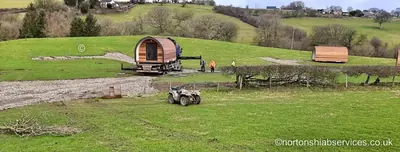 Two wooden glamping pods set down in a field after delivery