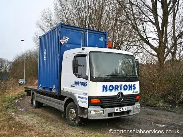 Nortons 7.5 tonne flatbed lorry carrying a small container
