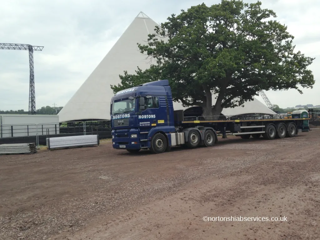 A Nortons artic and trailer parked under a large oak tree at the festival site