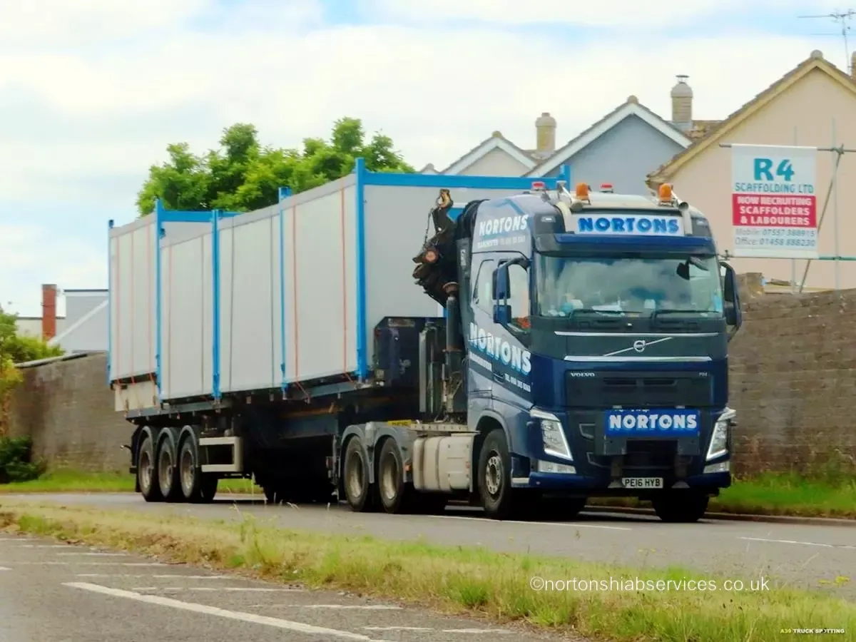 A Nortons hiab lorry with cabins passing through a Somerset village on the festival run