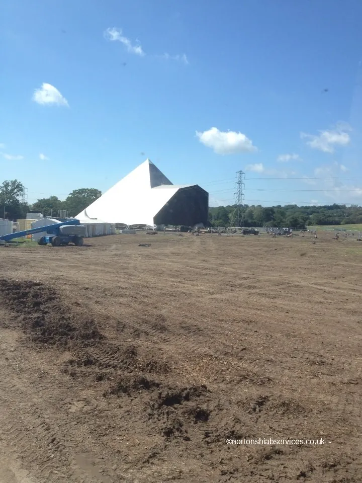 A large marquee standing alone on the emptied and churned Glastonbury festival field