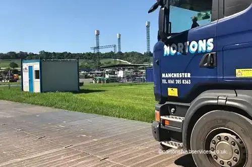 A Nortons Scania hiab standing on temporary trackway laid across the festival field