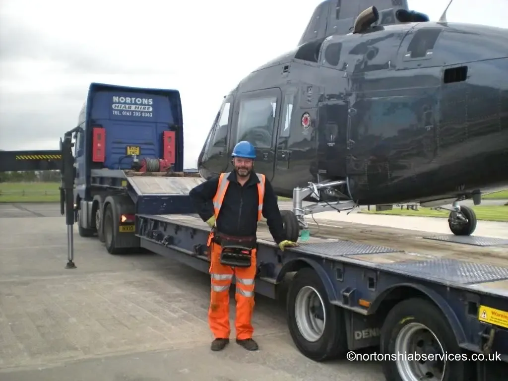 A Nortons driver / operator alongside a helicopter loaded on the low trailer at Blackpool Airport