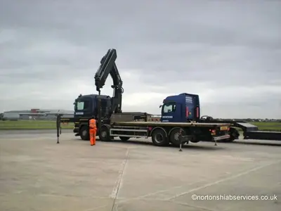 Nortons lorry with the crane set up and the stabiliser legs down on the airport apron
