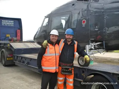 Two men in high visibility clothing beside the loaded helicopter at Blackpool Airport
