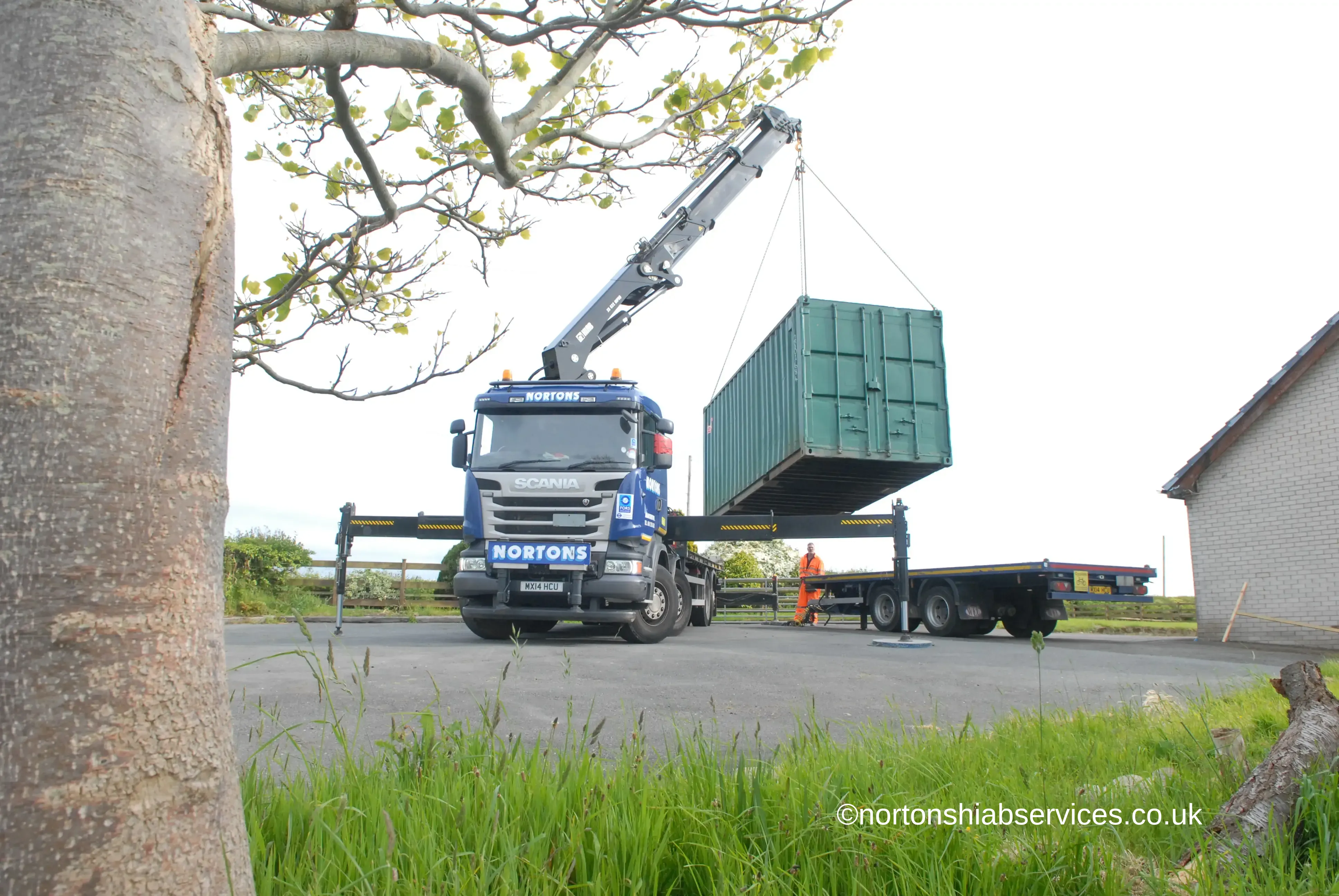 Hiab lifting a shipping container from a flatbed trailer