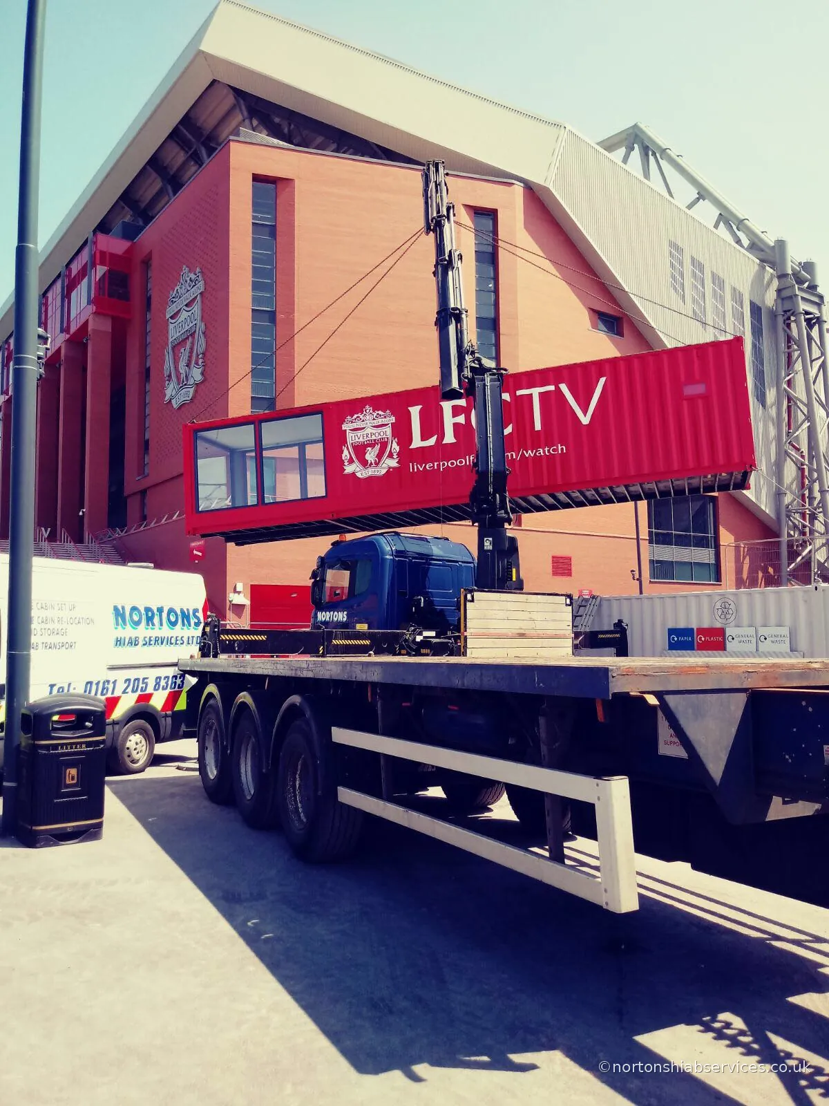 A Nortons hiab holding the red LFCTV studio unit on the slings alongside the stand at Anfield