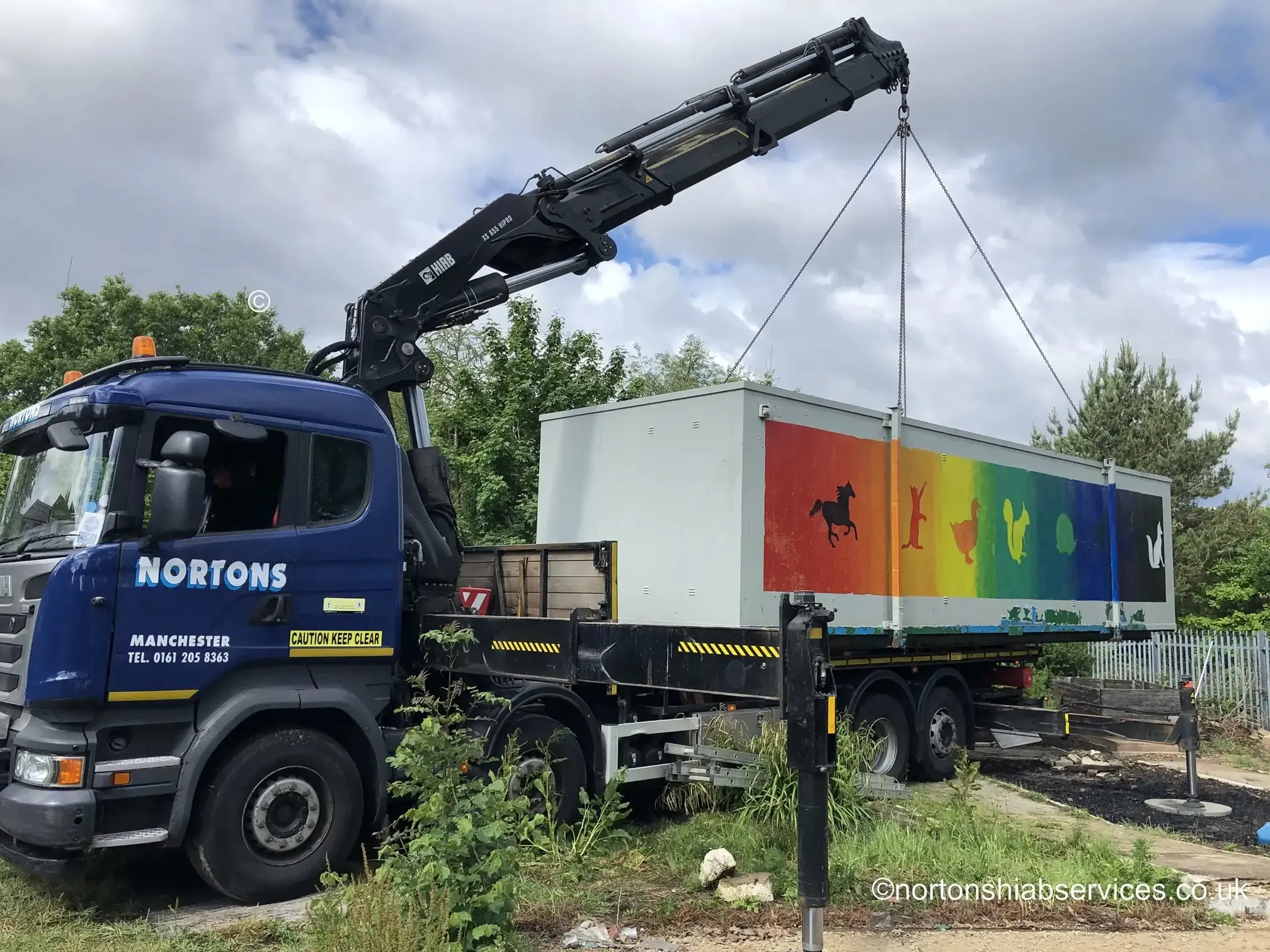 Rigid hiab placing a wide load unit at a community centre