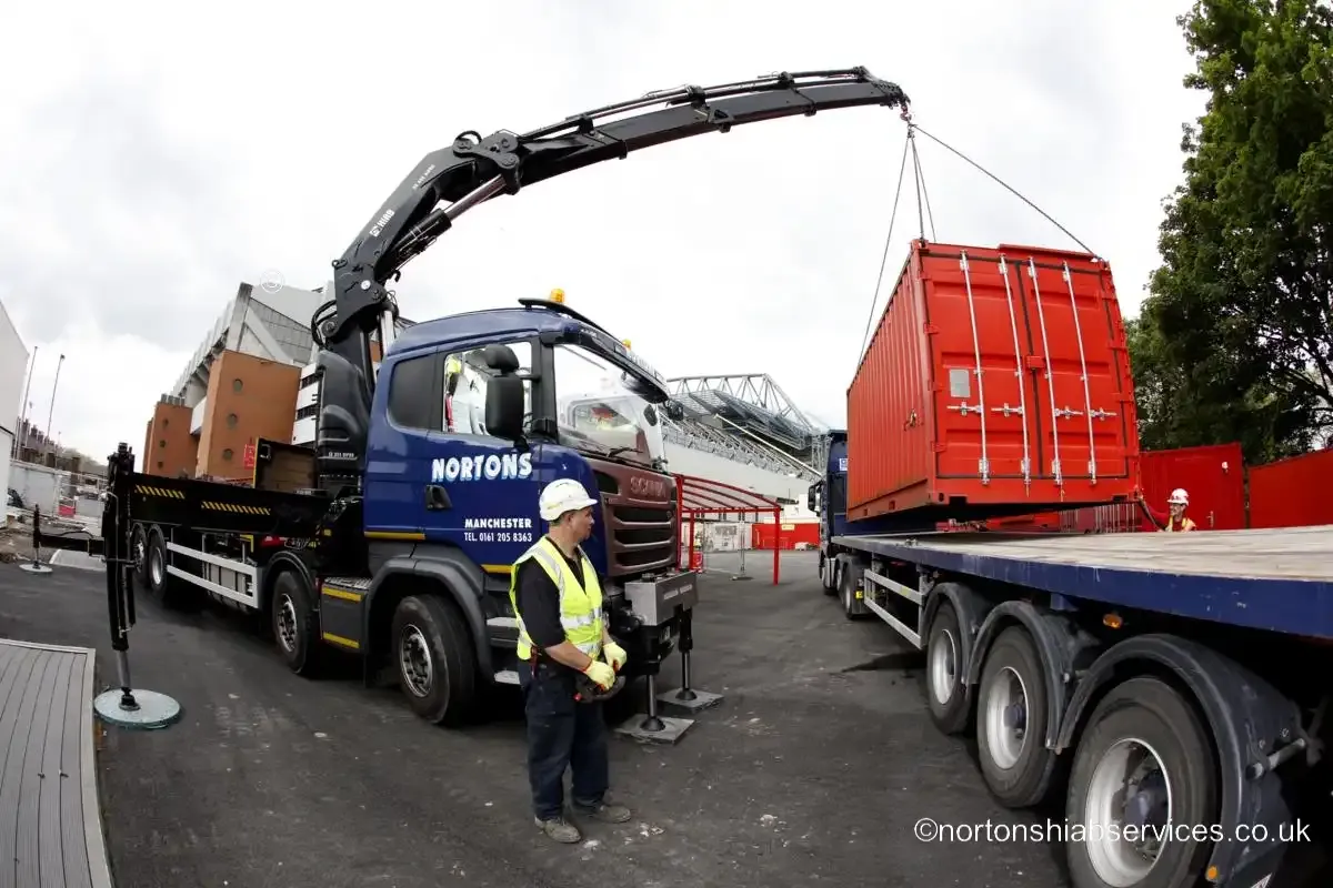 Nortons hiab lifting a red site unit clear of the trailer bed at Anfield