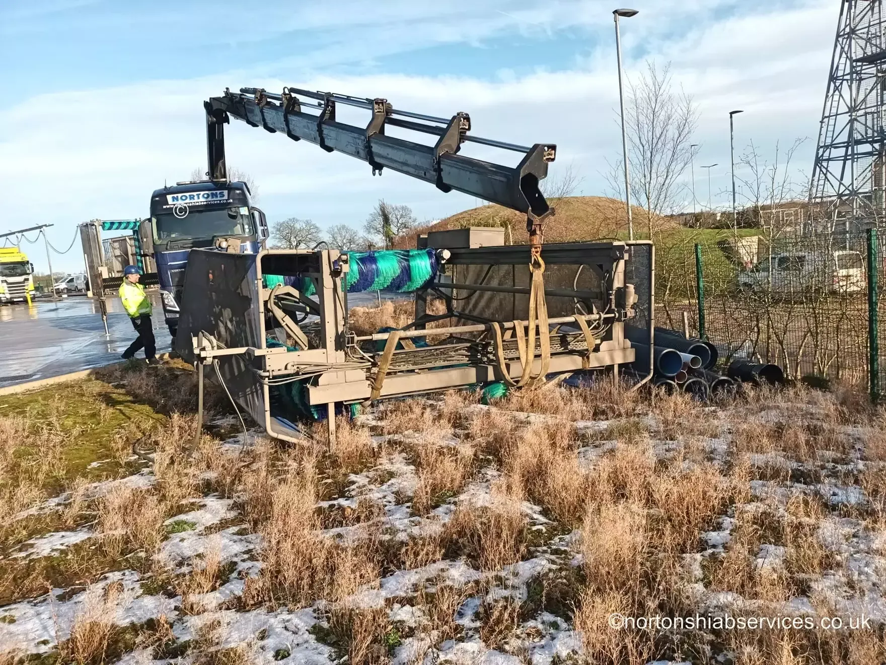 Nortons lorry loader placing a truck wash structure on rough ground
