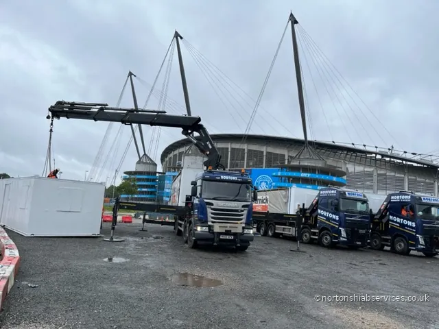 A Nortons hiab with the boom extended lifting a cabin at the Etihad Stadium in Manchester