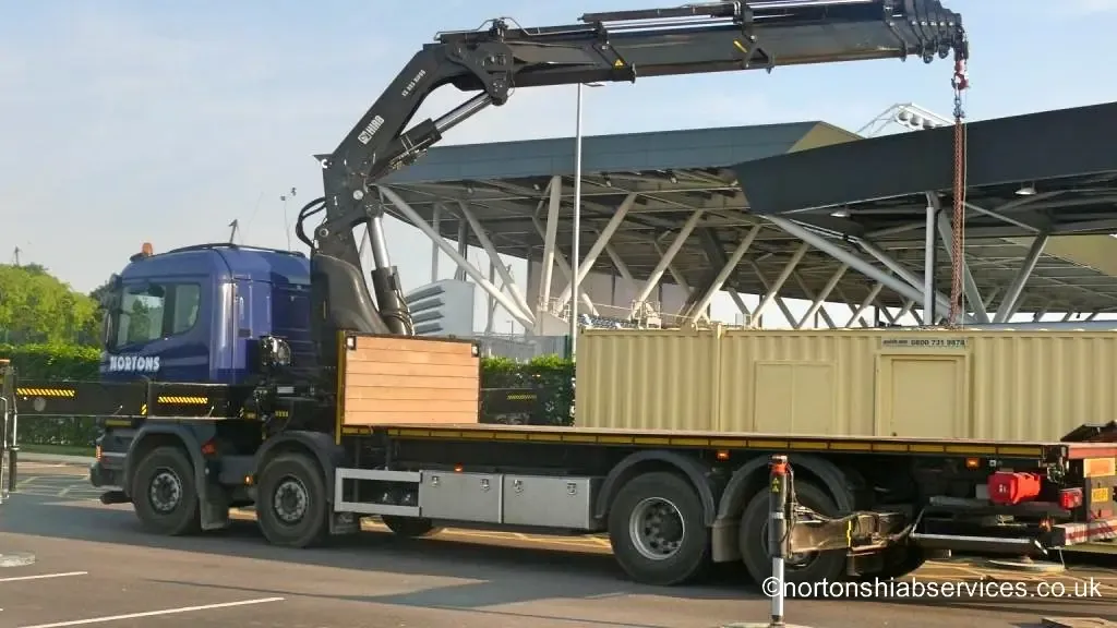 Nortons eight wheel hiab with a container on the deck outside the academy
