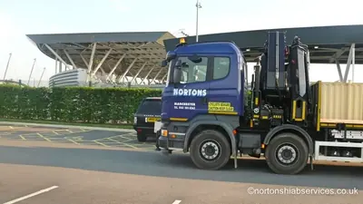 Nortons hiab with a container on the deck alongside the academy roofline
