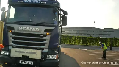Front of a Nortons Scania hiab with a worker in high visibility clothing directing it