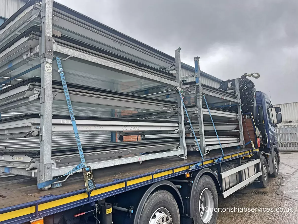Stillages of window frames strapped down on a Nortons flatbed