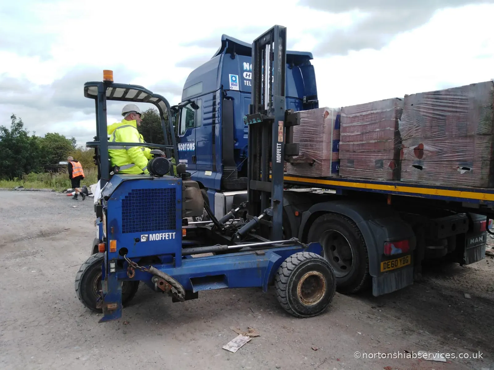 Nortons truck-mounted forklift fitted with a brick grab, taking a pack of bricks off the bed