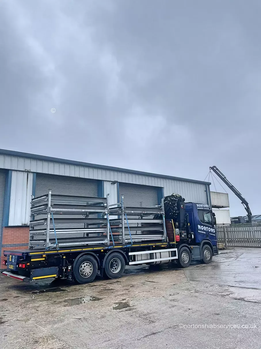 Nortons flatbed being loaded in the yard with a crane working behind it