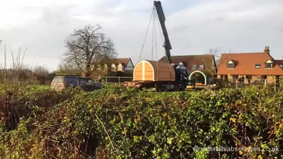 A timber glamping pod craned into position in a field at Bicester in Oxfordshire