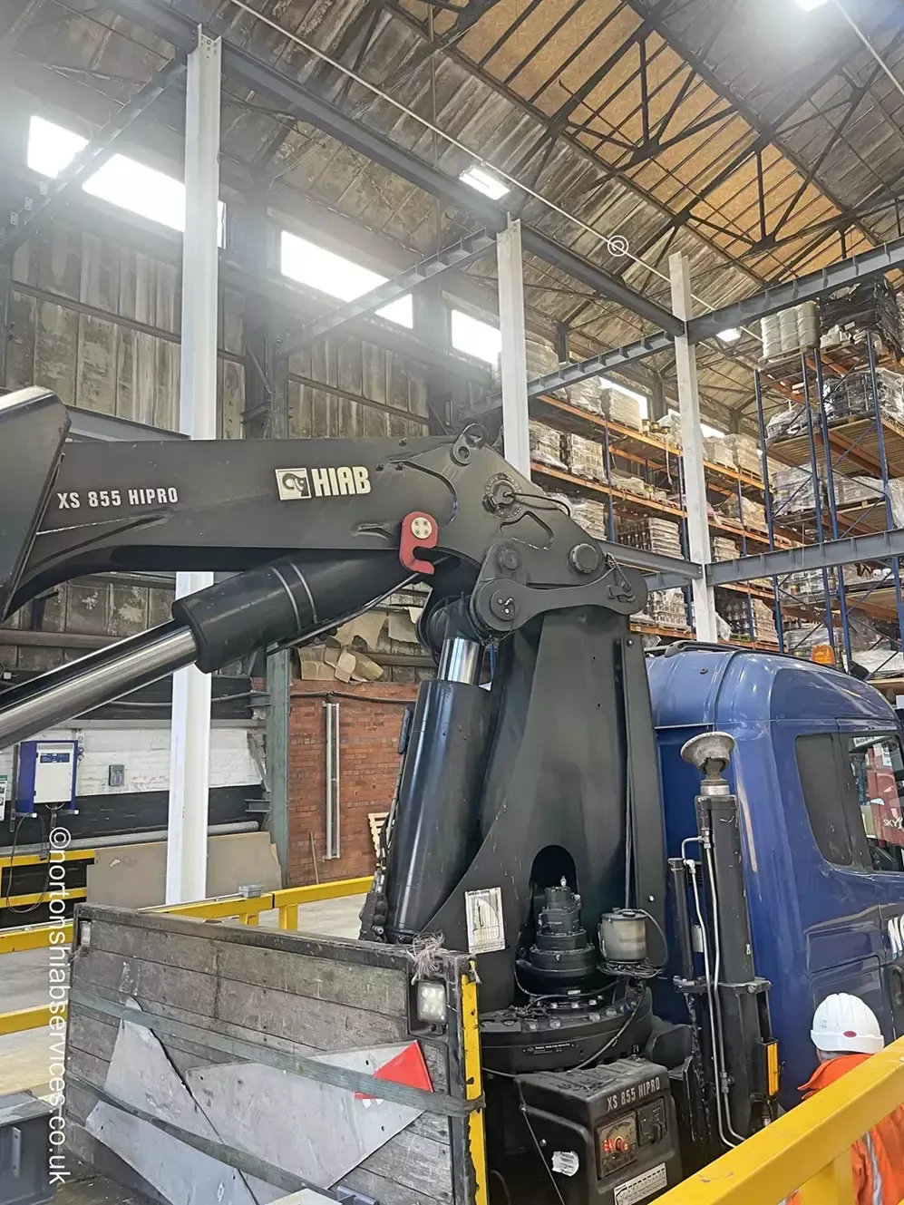 The boom and hydraulic rams of a HIAB X-HiPro 855 truck-mounted crane inside a warehouse