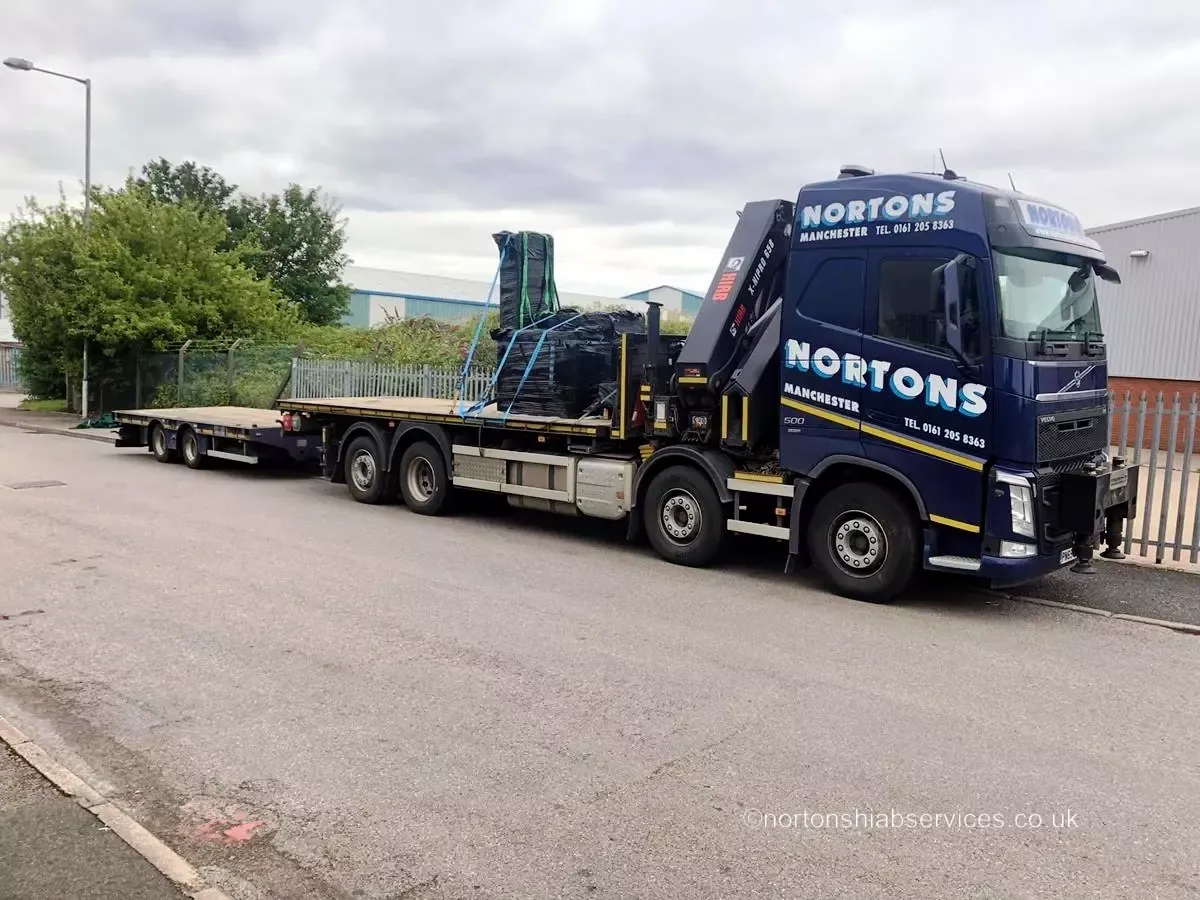 A Nortons eight-wheel rigid with a folded 858 hiab crane and a loaded trailer behind