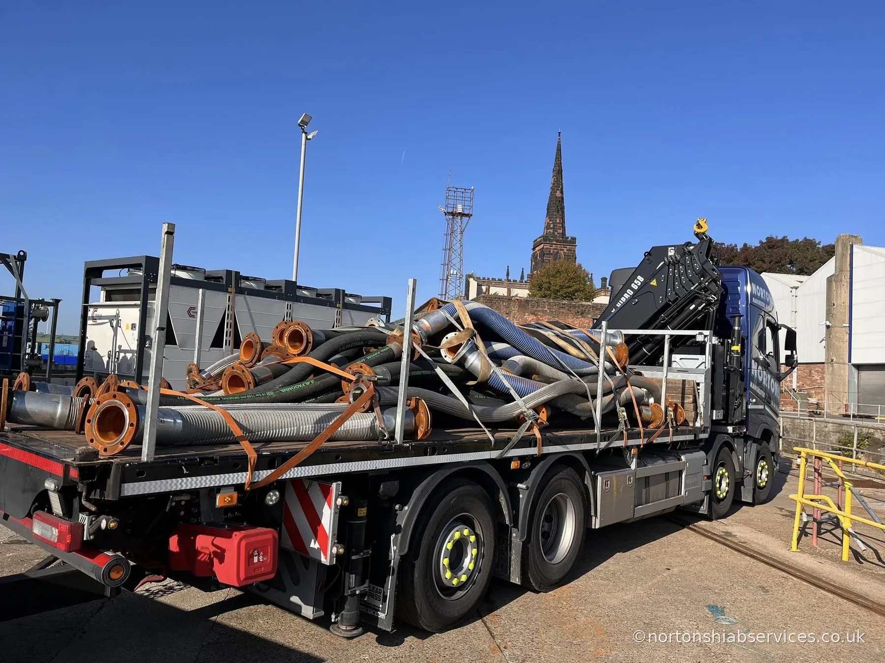 A Nortons Volvo rigid with a hiab crane loaded with flexible ducting and flanged pipework at Birkenhead